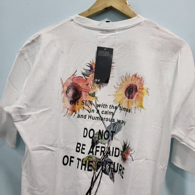 White, with a sunflower print featuring shades of yellow, orange, and brown, along with black text T-shirt