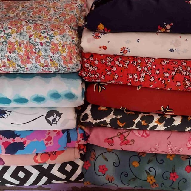 A variety of colors including floral patterns with pink, yellow, blue, and white; solid colors like red and navy; and prints in black and white. Fabric
