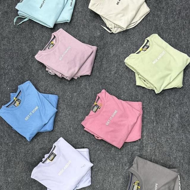 Various pastel colors including light blue, pink, lavender, light green, and a neutral beige, with text typically in white or a contrasting color. T-shirt