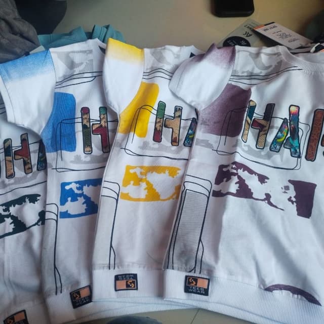 White, with accents of blue, yellow, and purple. The word 'HAI' has various color schemes. T-shirt
