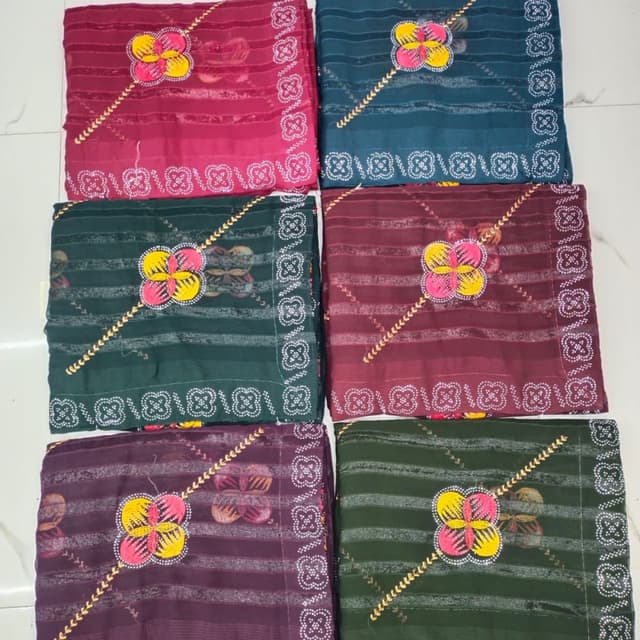 Various shades of burgundy, teal, deep green, and purple with contrasting floral accents in pink, yellow, and white. Saree