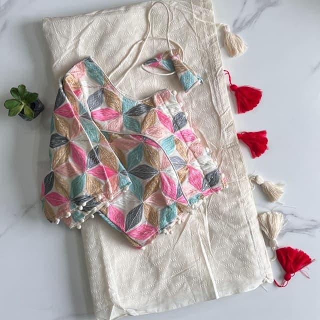 Multicolor embroidery on a white base. The embroidery includes pink, blue, grey, and beige shades. Blouse and Saree