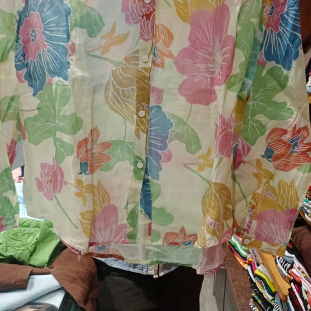 Pastel shades including pink, blue, green, orange, and yellow on a cream background. Shirt