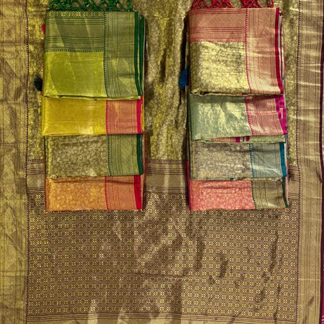 Vibrant shades of green, yellow, orange, and pink, with gold and contrasting borders. Sarees