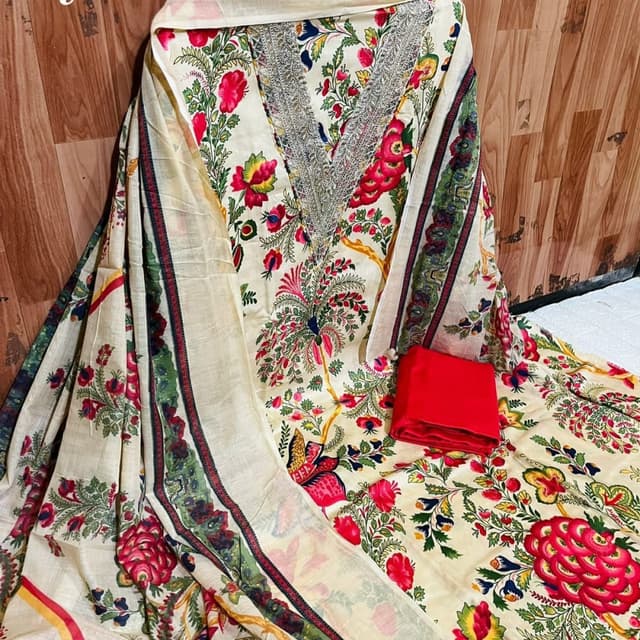 Cream base with a vibrant floral print in red, green, yellow, and blue. The dupatta has a cream base with a green and maroon border. Salwar Kameez Suit