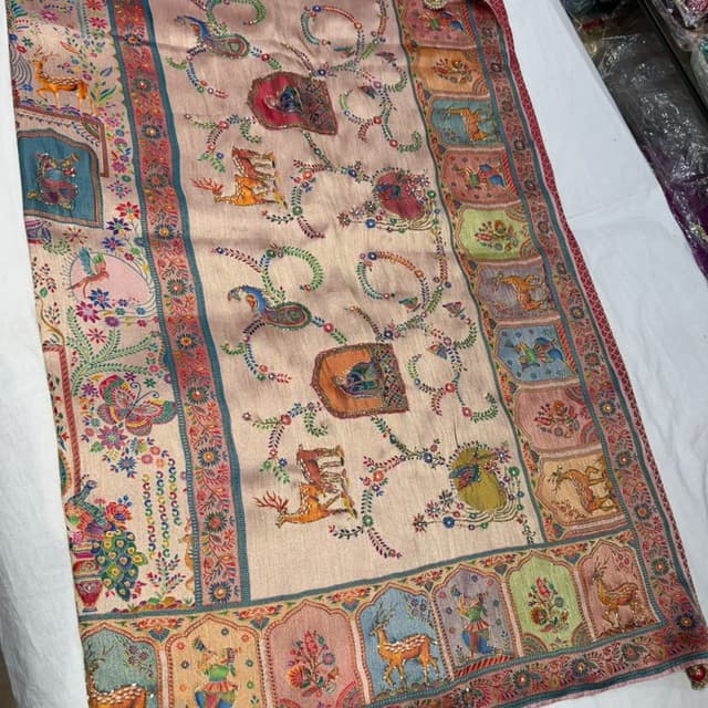 Soft beige, with accents of red, teal, pink, orange, green, blue, and gold. Saree