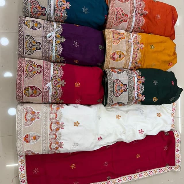 Various, including teal, purple, orange, yellow, red, white, and dark green. Each fabric is a solid color, with contrasting embellished borders. Fabric or Textile