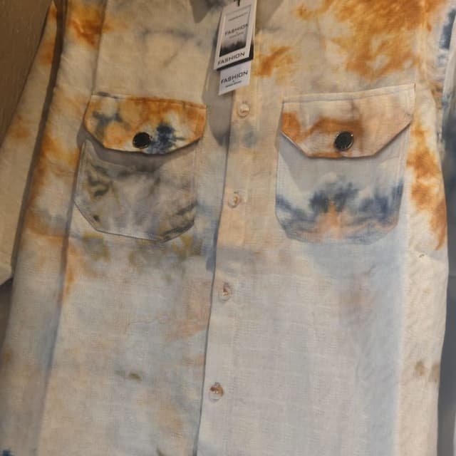 Off-white base with tie-dye effects in shades of brown, tan, and blue. Shirt