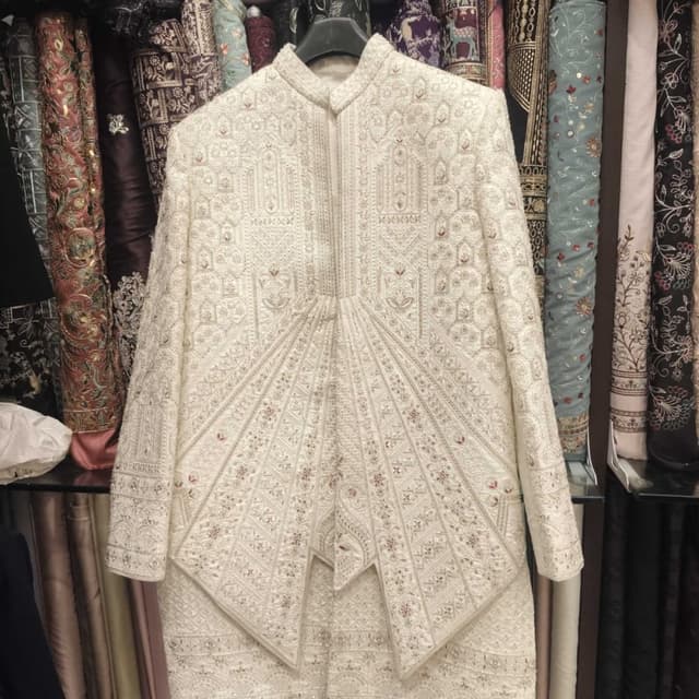 Ivory white with subtle hints of red and silver accents Sherwani