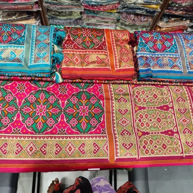 Vibrant mix of fuchsia pink, crimson red, emerald green, golden yellow, and hints of turquoise. Saree