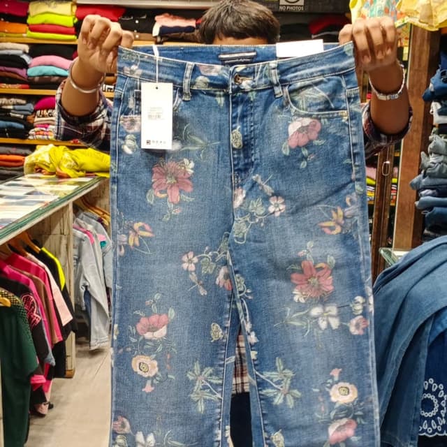 Blue base with multicolored floral print in pink, white, green, and yellow Jeans