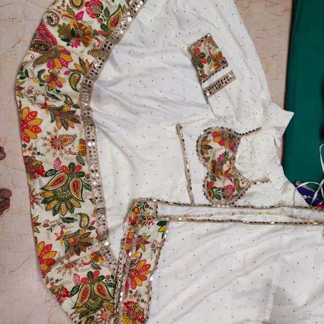 Off-white base with multicolor floral embroidery (red, pink, green, yellow, orange) and gold accents Lehenga Choli