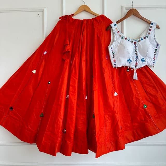Vibrant orange skirt with a stark white sleeveless blouse featuring multicolored embroidery Lehenga Choli