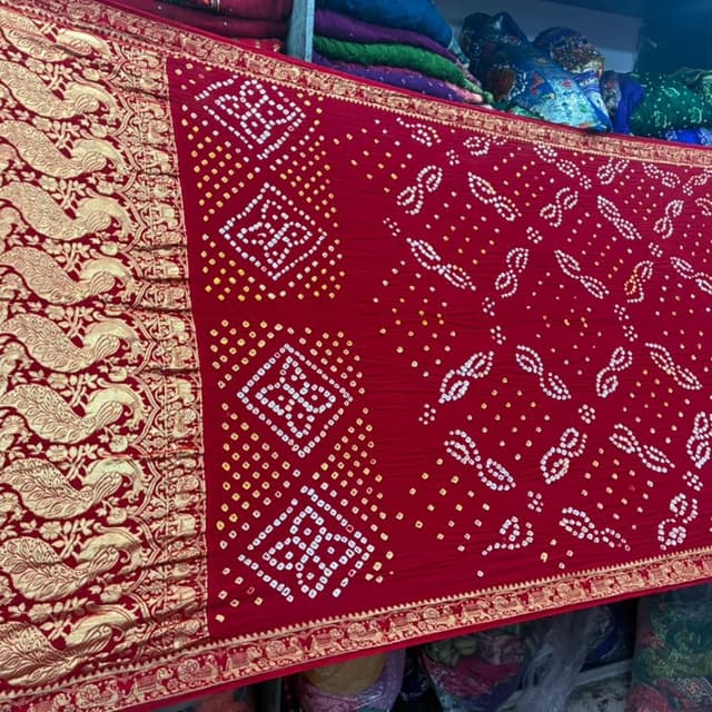 Deep red base with white, yellow, and metallic gold accents Saree