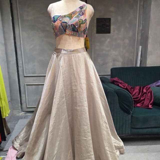 Champagne gold skirt with a multi-colored patchwork blouse featuring pink, blue, green, and orange accents. Lehenga Choli