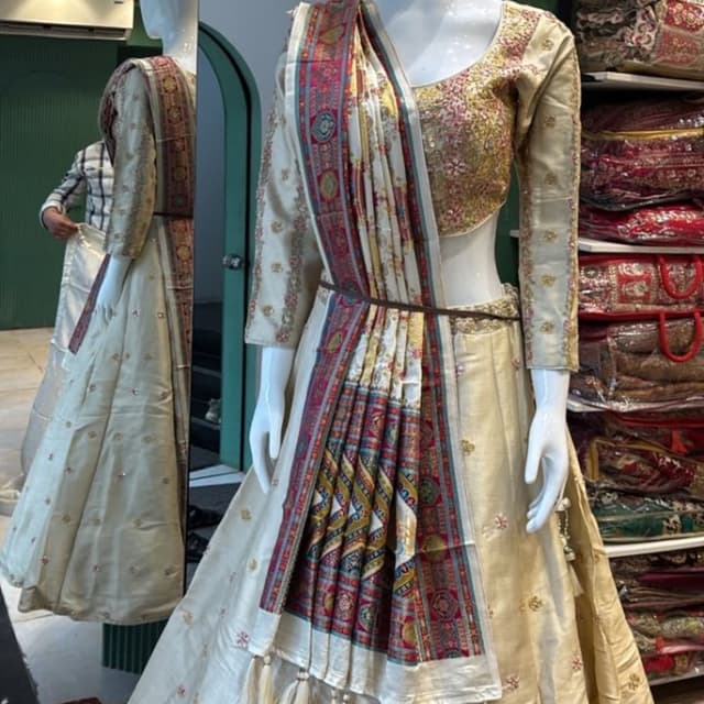 Off-white or cream base with multi-colored patola print borders in red, blue, and yellow Lehenga Choli