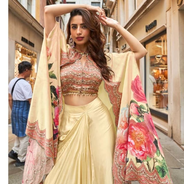 Light gold, soft yellow base with vibrant pink, coral, and green floral accents Lehenga Choli with Kaftan-style Cape