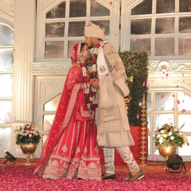 Red and Gold (Bride), Beige and Gold (Groom) Lehenga Choli (Bride), Sherwani (Groom)
