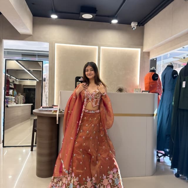 Rust orange base with multi-colored floral embroidery in pink, blue, and white tones Lehenga Choli